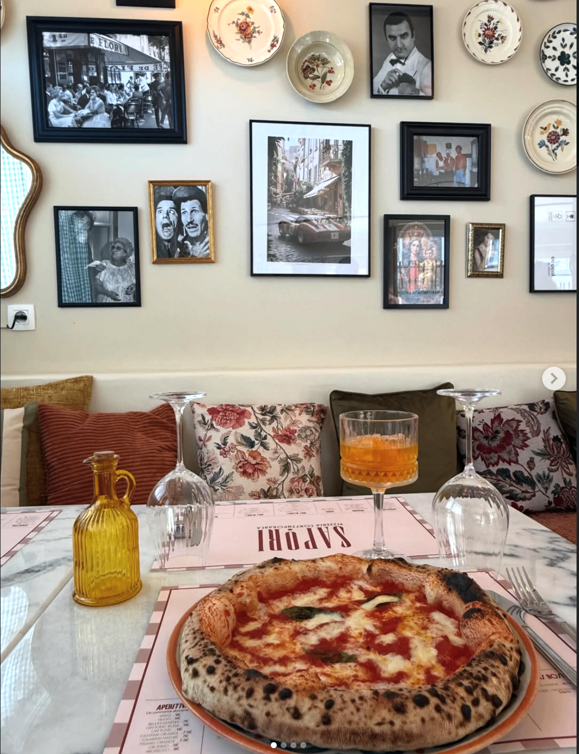 Salle SAPORI : mur galerie d'assiettes et de photos, pizza napolitaine sur table en marbre